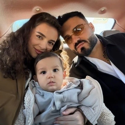 Jador &icirc;n mașină, pe bancheta din spate, &icirc;mbrăcat &icirc;n negru și alb, st&acirc;nd alături de Oana Ciocan și de fiul lor pe care femeia &icirc;l ține &icirc;n brațe