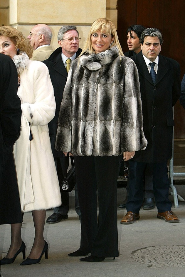 Antonella&nbsp;Ferrari, unica fiică a lui Piero Ferrari, z&acirc;mbitoare, cu părul blond, &icirc;mbrăcată &icirc;n pantaloni negri evazați și haină de blană gri cu alb