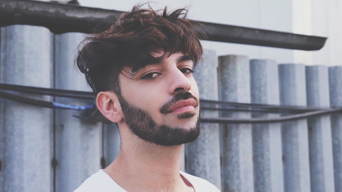 David Pușcaș &icirc;ntr-un tricou alb, fotografiat din profil, cu barbă și cercel &icirc;n spr&acirc;nceană