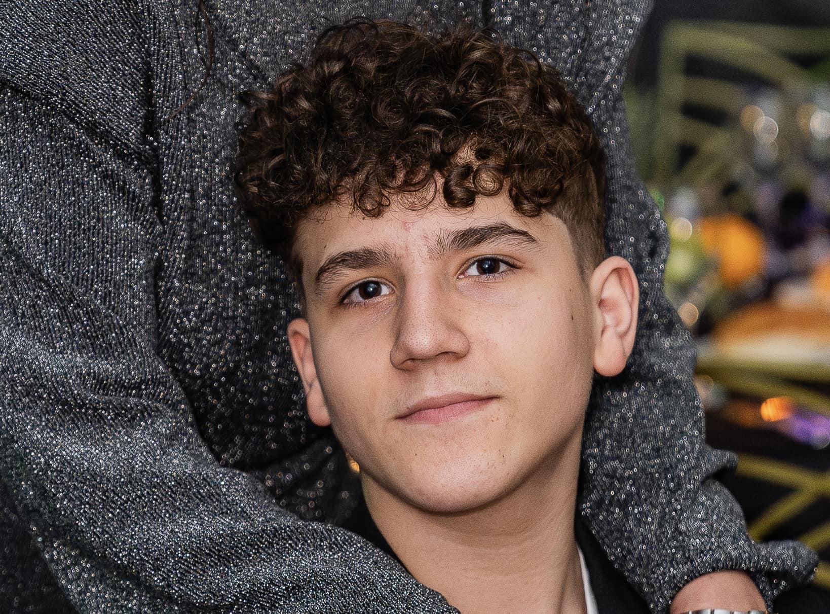 Dina, fiul Marei Bănică z&acirc;mbitor, &icirc;mbrăcat &icirc;n sacou negru și tricou alb, &icirc;n timp ce mama lui l-a cuprins cu brațele &icirc;n jurul g&acirc;tului