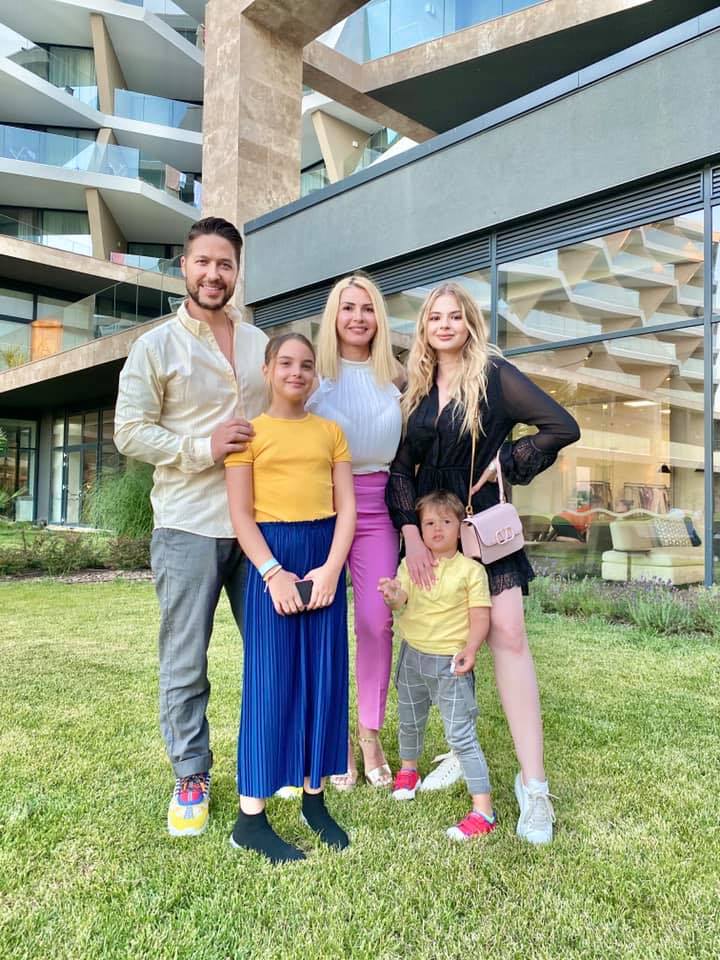 Jorge alături de soție și de copii, st&acirc;nd toți z&acirc;mbitori la poză, pe un spațiu verde, cu gazon, &icirc;n fața unei clădiri din sticlă