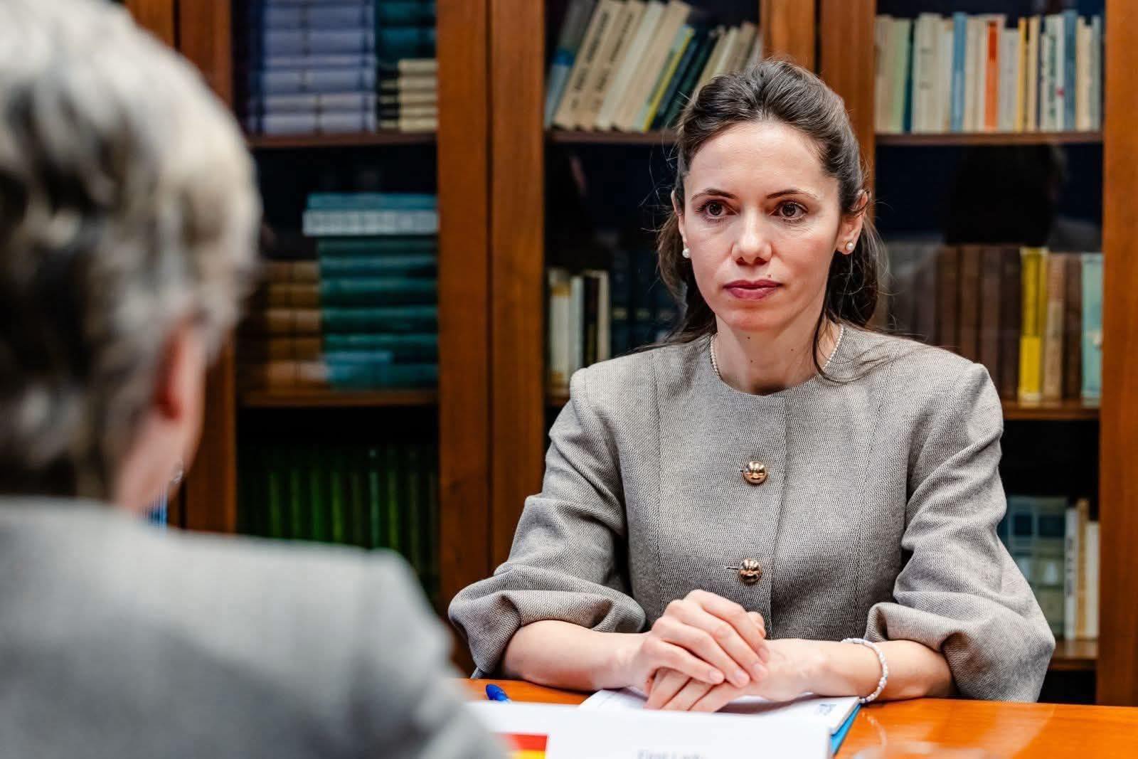 Mirabela Grădinaru, partenera președintelui Nicușor Dan, st&acirc;nd serioasă la birou, &icirc;n cadrul unei &icirc;nt&acirc;lniri oficiale, &icirc;mbrăcată &icirc;ntr-o rochie gri cu nasturi aurii supradimensionați