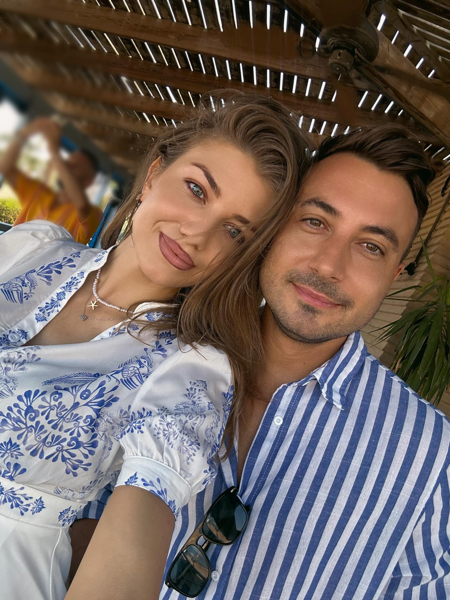 Codruța Filip și Valentin Sanfira făc&acirc;ndu-și o fotografie &icirc;n timp ce stăteau &icirc;mpreună la masa unei terase, &icirc;mbrăcați asortat &icirc;n alb cu albastru, &icirc;n timpul unei vacanțe