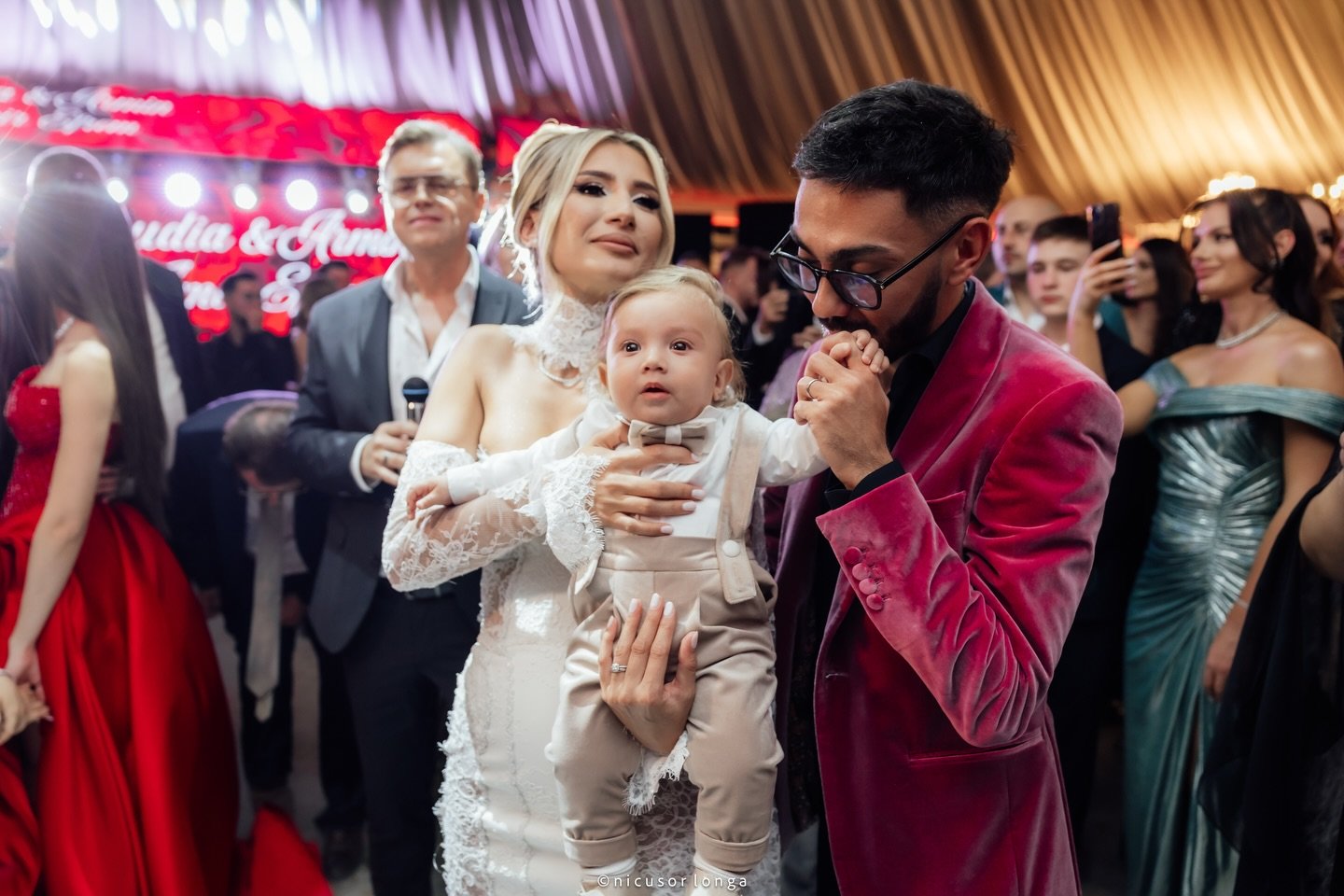 Claudia Puican țin&acirc;nd-ul &icirc;n brațe pe fiul ei Amir, &icirc;n timp ce Armin Nicoară &icirc;i pupă m&acirc;na micuțului, la nunta lor din 2025