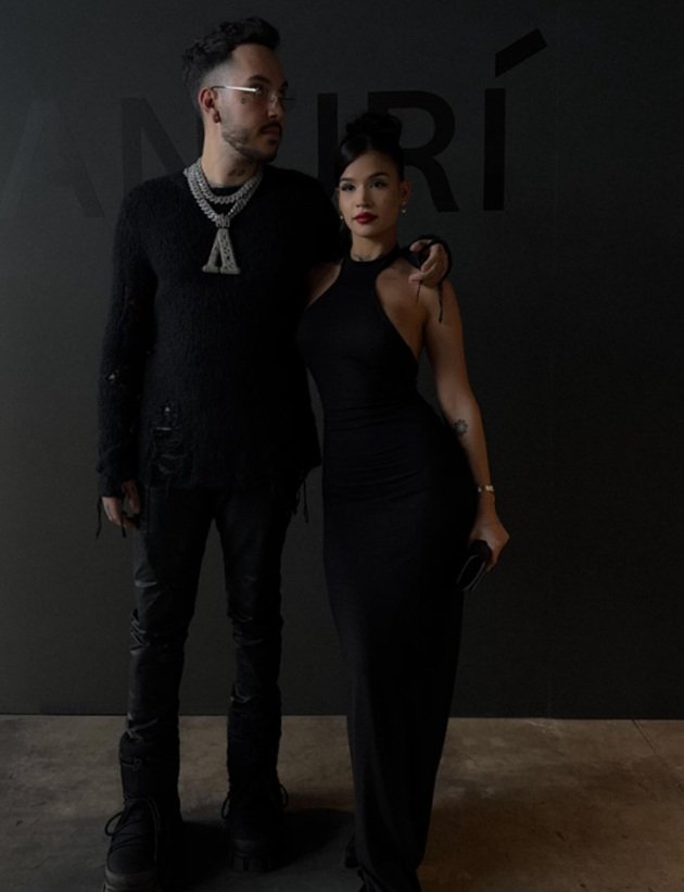 Azteca cu ochelarii de soare la ochi la interior, țin&acirc;nd-o pe Dana de umăr, &icirc;n timp ce erau am&acirc;ndoi &icirc;mbrăcați &icirc;n negru