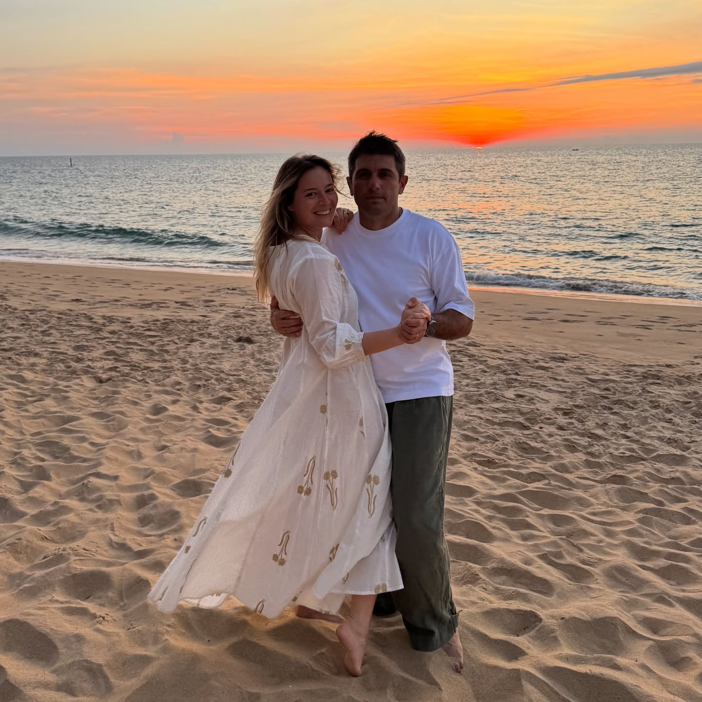 Laura Cosoi și soțul ei Cosmin Curticăpean, dans&acirc;nd pe plajă, la apus, &icirc;mbrăcați am&acirc;ndoi &icirc;n alb și nuanțe neutre