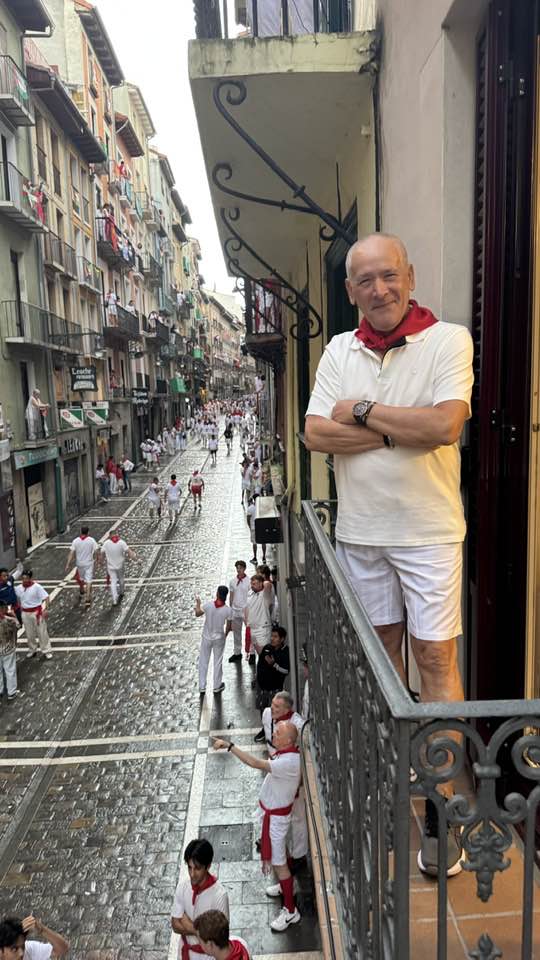 Medicul Cristian&nbsp;Staicu la balconul unui apartament dintr-o clădire veche, &icirc;n timpul unei vacanțe, &icirc;mbrăcat &icirc;n alb, cu o eșarfă roșie la g&acirc;t, st&acirc;nd cu m&acirc;inile &icirc;n s&acirc;n