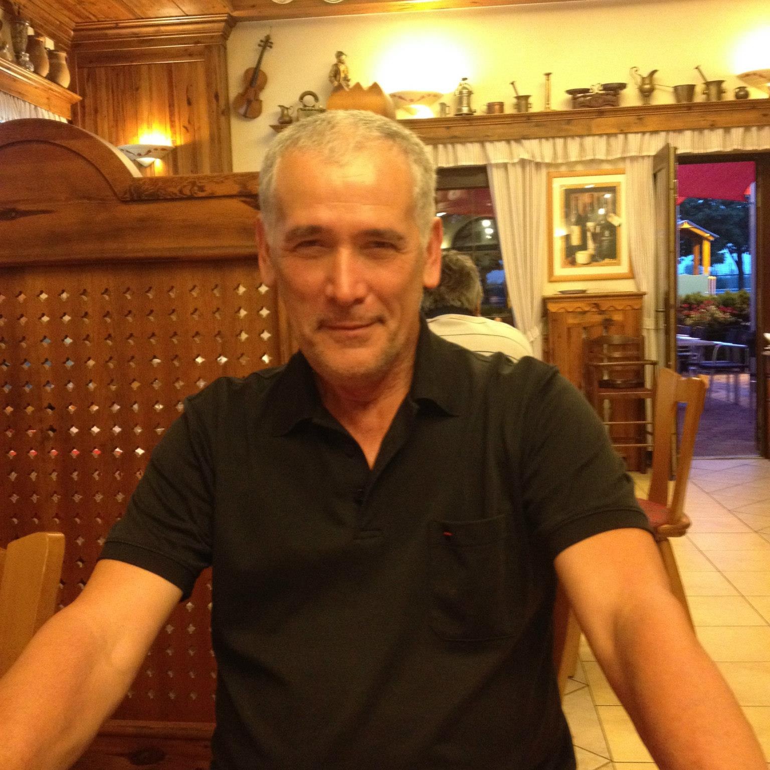 Medicul Cristian&nbsp;Staicu la masa unui restaurant, st&acirc;nd cu m&acirc;inile pe masă, z&acirc;mbitor, &icirc;ntr-un tricou negru cu guler