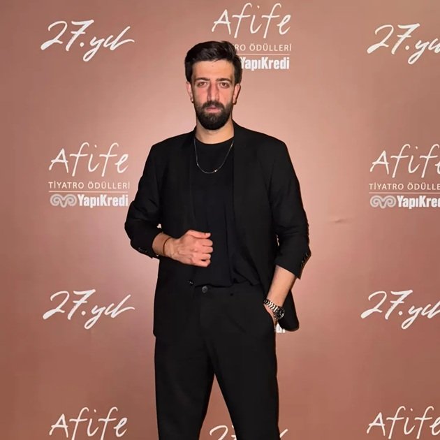 actorul turc Ramazan&nbsp;Tetik&nbsp;la un eveniment public, &icirc;mbrăcat din cap p&acirc;nă &icirc;n picioare &icirc;n negru, st&acirc;nd cu o m&acirc;nă &icirc;n buzunar și cu cealaltă țin&acirc;ndu-se de sacou