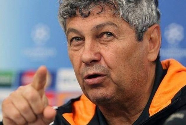 Mircea Lucescu serios, &icirc;n timpul unei discuții oficiale, arăt&acirc;nd cu degetul &icirc;ntr-o direcție, &icirc;n timp ce era &icirc;mbrăcat &icirc;ntr-un hanorac cu o glugă portocalie