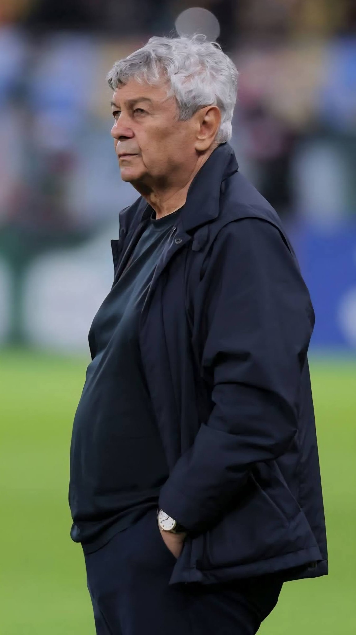 Mircea Lucescu pe marginea terenului, cu m&acirc;inile &icirc;n buzunar, privind serios și cu atenție meciul