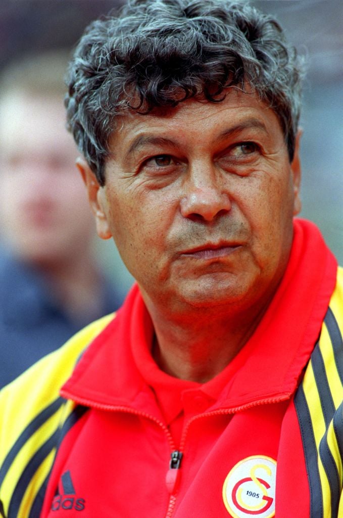 Mircea Lucescu privind &icirc;ntr-o parte, &icirc;n timp ce era &icirc;mbrăcat &icirc;ntr-o bluză de trening &icirc;n culorile Rom&acirc;niei