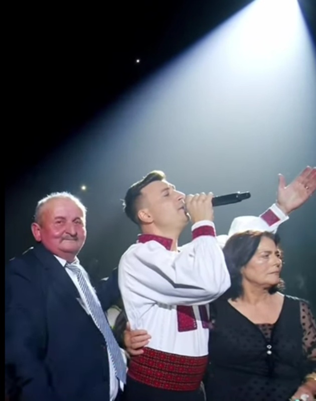 Valentin Sanfira alături de părinții lui, pe scenă, &icirc;n timpul unui concert, &icirc;n timp ce mama lui pl&acirc;ngea și &icirc;l &icirc;mbrățișa str&acirc;ns, iar tatăl privea &icirc;n jur cu m&acirc;ndrie