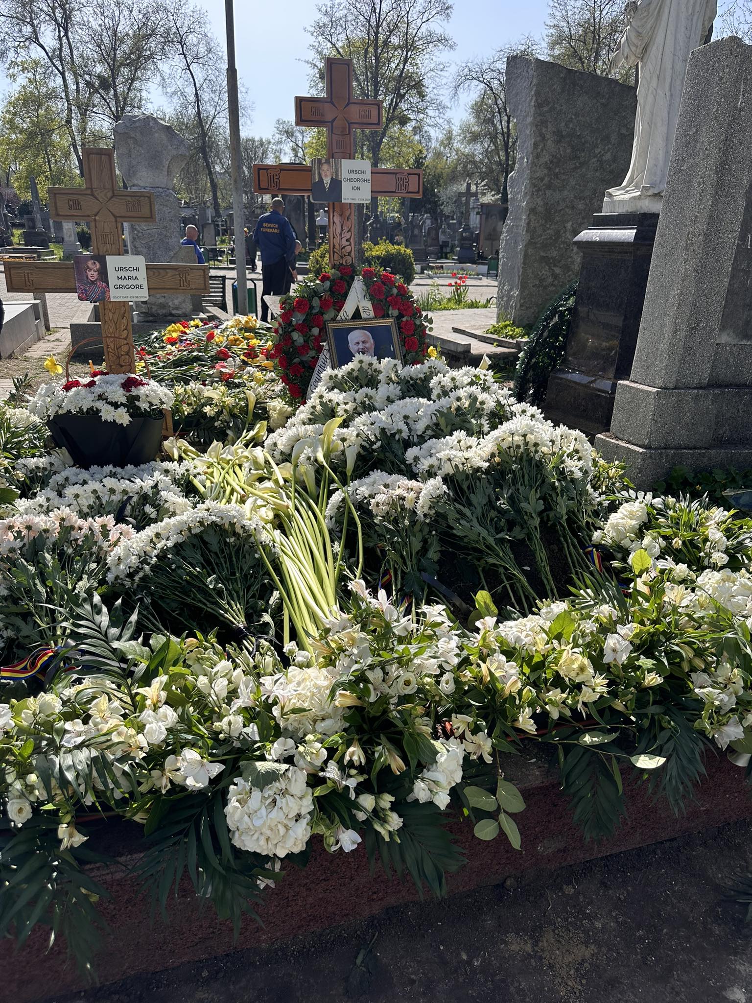 Mormântul lui Gheorghe Urschi acoperit de flori albe și de un tablou cu fotografia lui