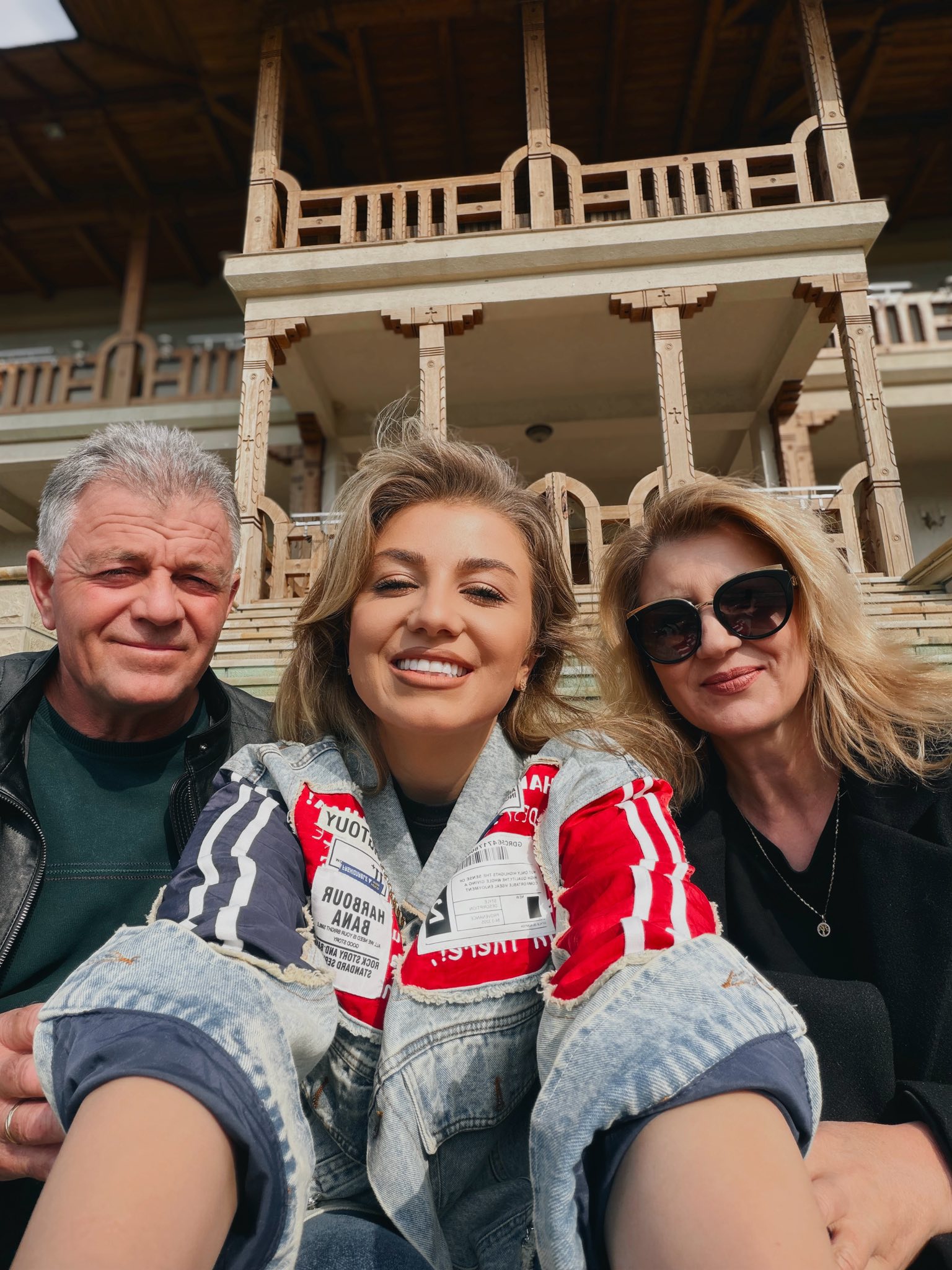 Codruța Filip alături de părinții ei, st&acirc;nd la soare, pe scările din fața unei mănăstiri