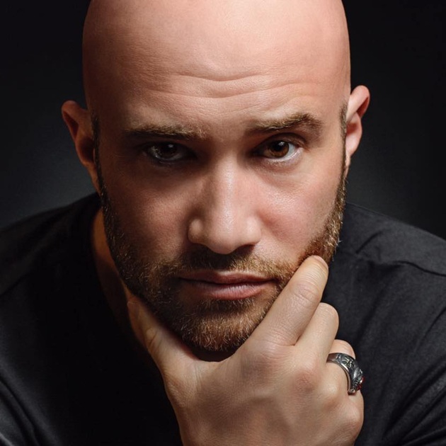 Portret al lui Mihai Bendeac care stă cu m&acirc;na &icirc;n barbă, &icirc;n timp ce era &icirc;mbrăcat &icirc;ntr-un tricou negru și cu un inel de mari dimensiuni pe deget