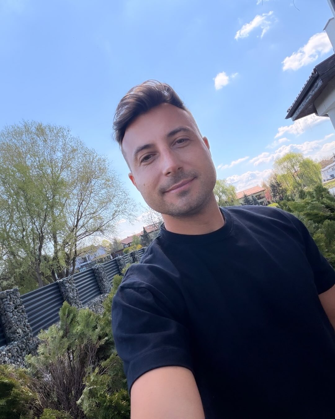 Valentin&nbsp;Sanfira &icirc;ntr-un tricou negru, făc&acirc;ndu-și un selfie &icirc;n curte, printre copaci și alte plante