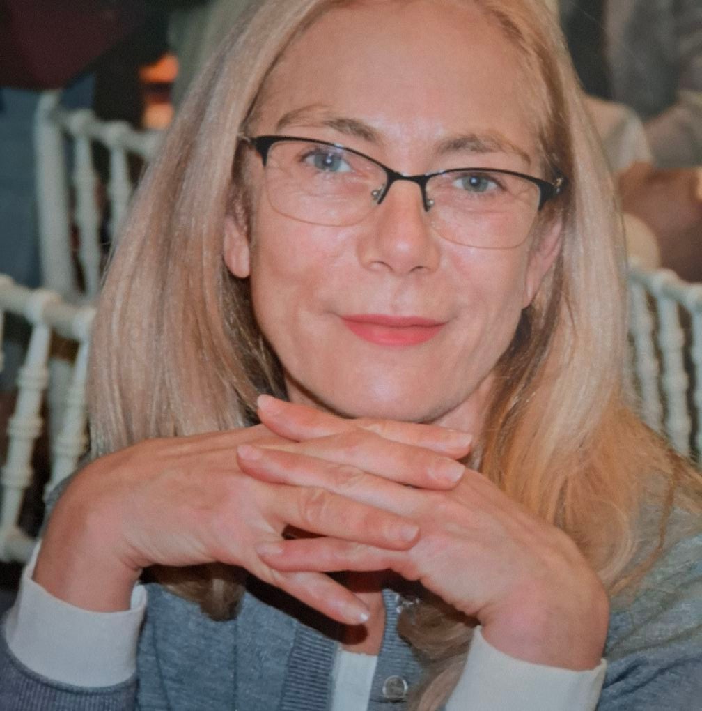 Daniela&nbsp;Jovrea z&acirc;mbitoare, cu părul blond tuns p&acirc;nă la umeri, &icirc;mbrăcată &icirc;n alb și gri, sprijinindu-și bărbia de m&acirc;inile &icirc;ncrucișate