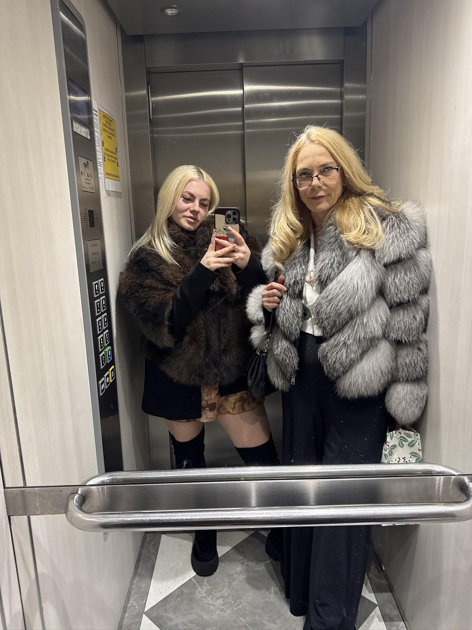 Daniela&nbsp;Jovrea &icirc;n lift alături de fiica ei Brigitta, care făcea o fotografie &icirc;n oglindă, &icirc;n timp ce am&acirc;ndouă purtau haine de blană