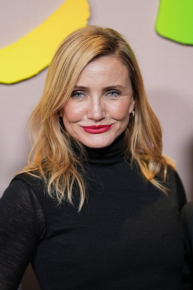 Cameron Diaz z&acirc;mbitoare, cu părul ondulat la v&acirc;rfuri, &icirc;mbrăcată &icirc;n negru, cu ruj rușu pe buze