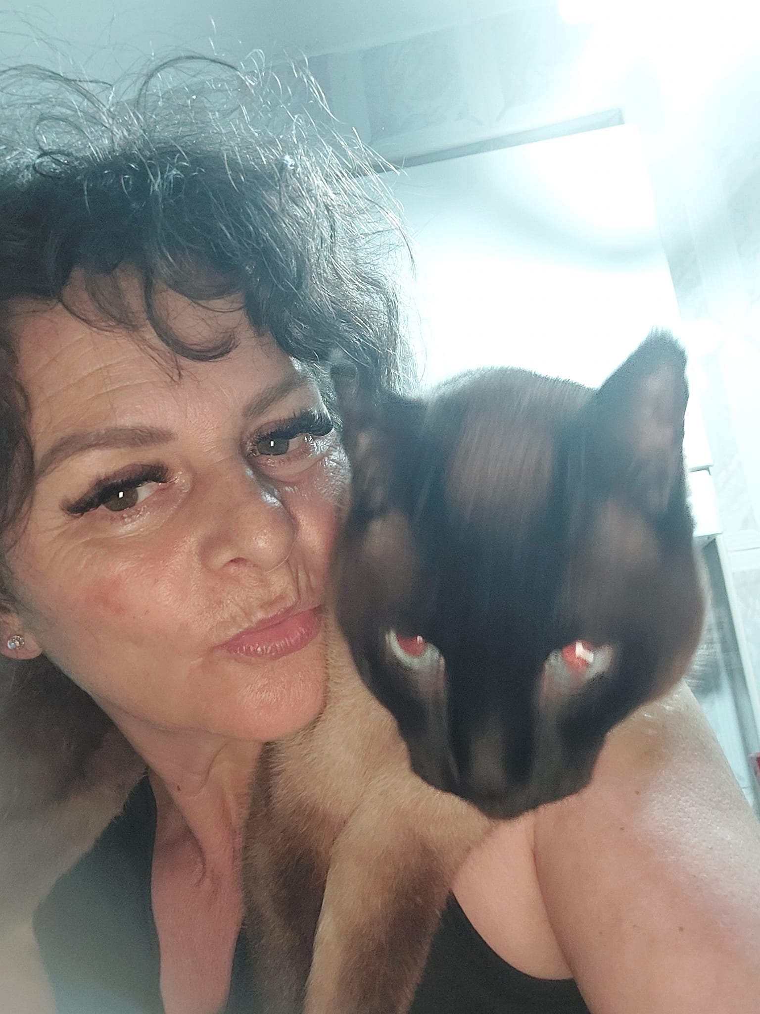 Alpinista Cristina Dinu făc&acirc;ndu-și un selfie, &icirc;n timp ce ținea &icirc;n brațe o pisică neagră cu maro