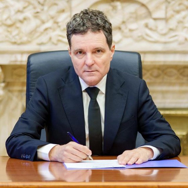 președintele Nicușor Dan st&acirc;nd la birou, &icirc;mbrăcat &icirc;n costum, semn&acirc;nd un document important