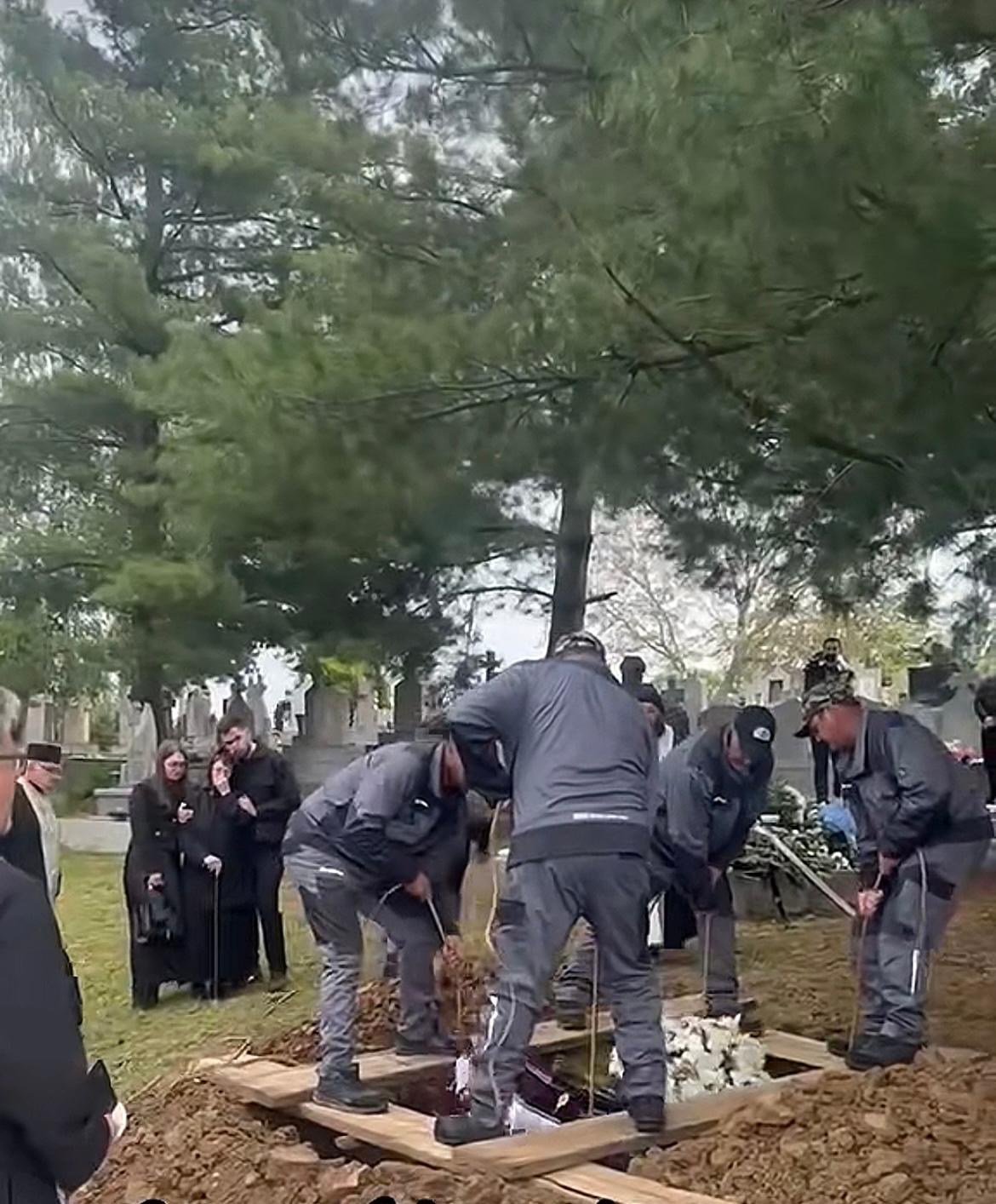 Mama lui Ioan Isaiu la înmormântarea actorului, alături de rude și apropiați, privind cu durere cum groparii pun sicriul în groapă