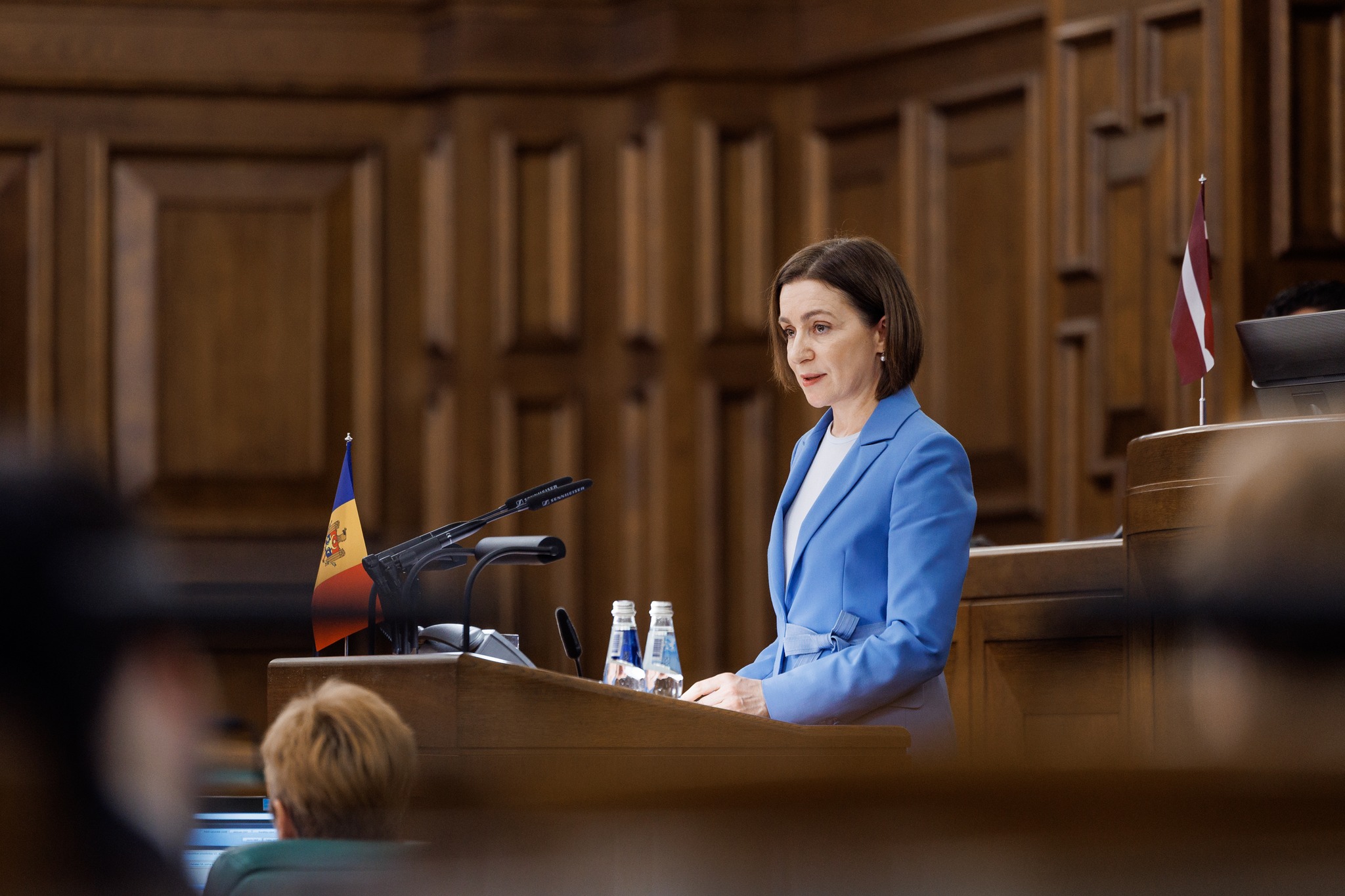 Maia Sandu vorbind &icirc;n fața unei mulțimi, la microfon, &icirc;n timp ce era &icirc;mbrăcată &icirc;ntr-o bluză albă și un costum albastru