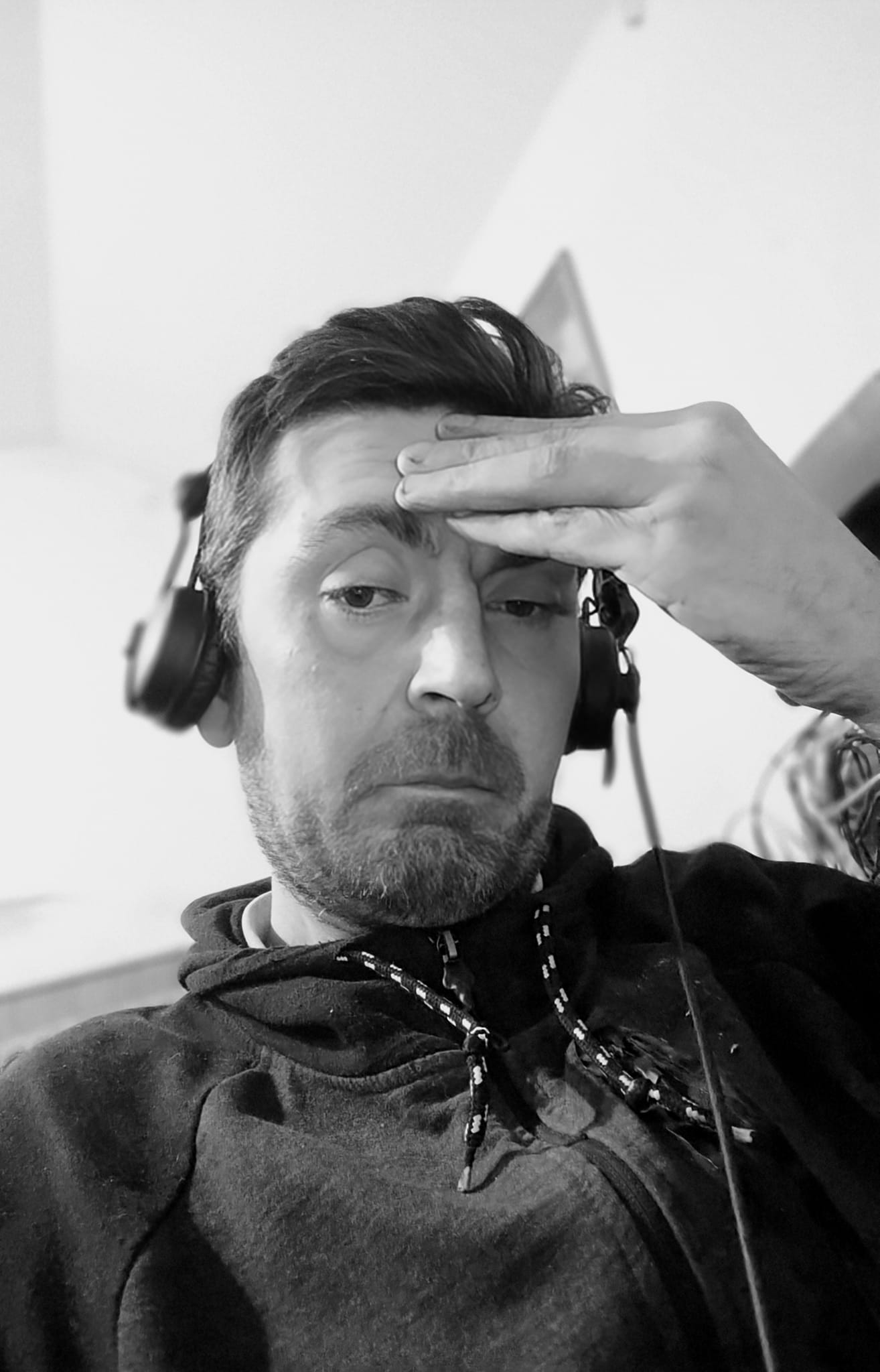 Imagine alb-negru cu Bogdan Ghiță, cunoscut publicului drept DJ Bob Fontana, care avea căștile pe urechi și se ținea cu m&acirc;na de frunte