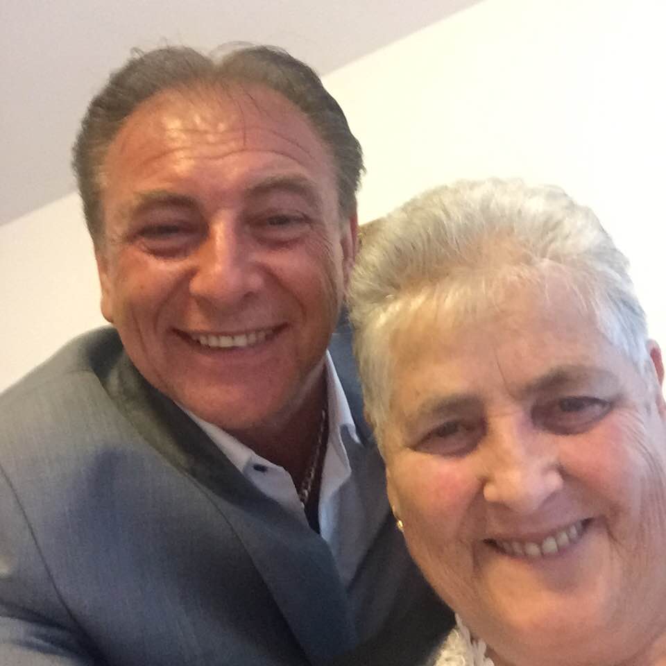 Nicolae Furdui Iancu z&acirc;mbitor, &icirc;n costum gri, alături de mama lui, Viorica Furdui, tunsă scurt, cu părul alb