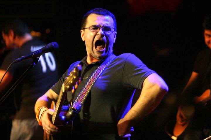 Mihai Mărgineanu pe scenă, prins &icirc;ntr-o imagine cu gura deschisă &icirc;n timp ce c&acirc;nta, av&acirc;nd at&acirc;rnată e g&acirc;t o chitară