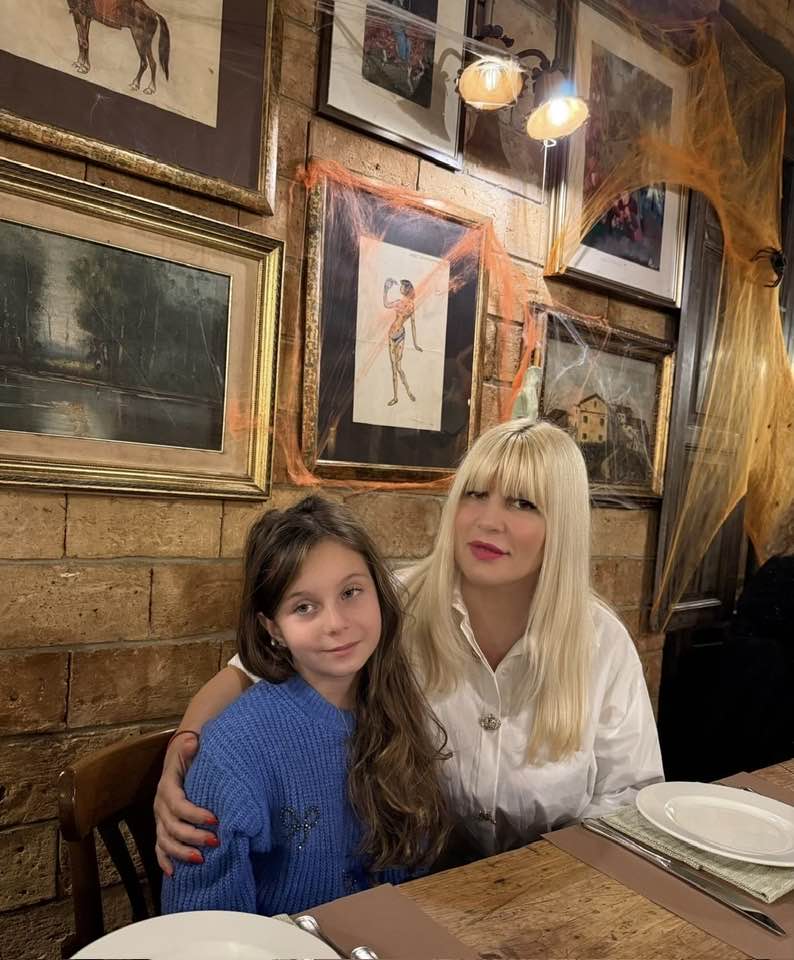 Elena Udrea și fiica ei st&acirc;nd &icirc;mbrățișate la aceeași masă, la un restaurant cu decor rustic, cu farfuriile și tac&acirc;murile &icirc;n față