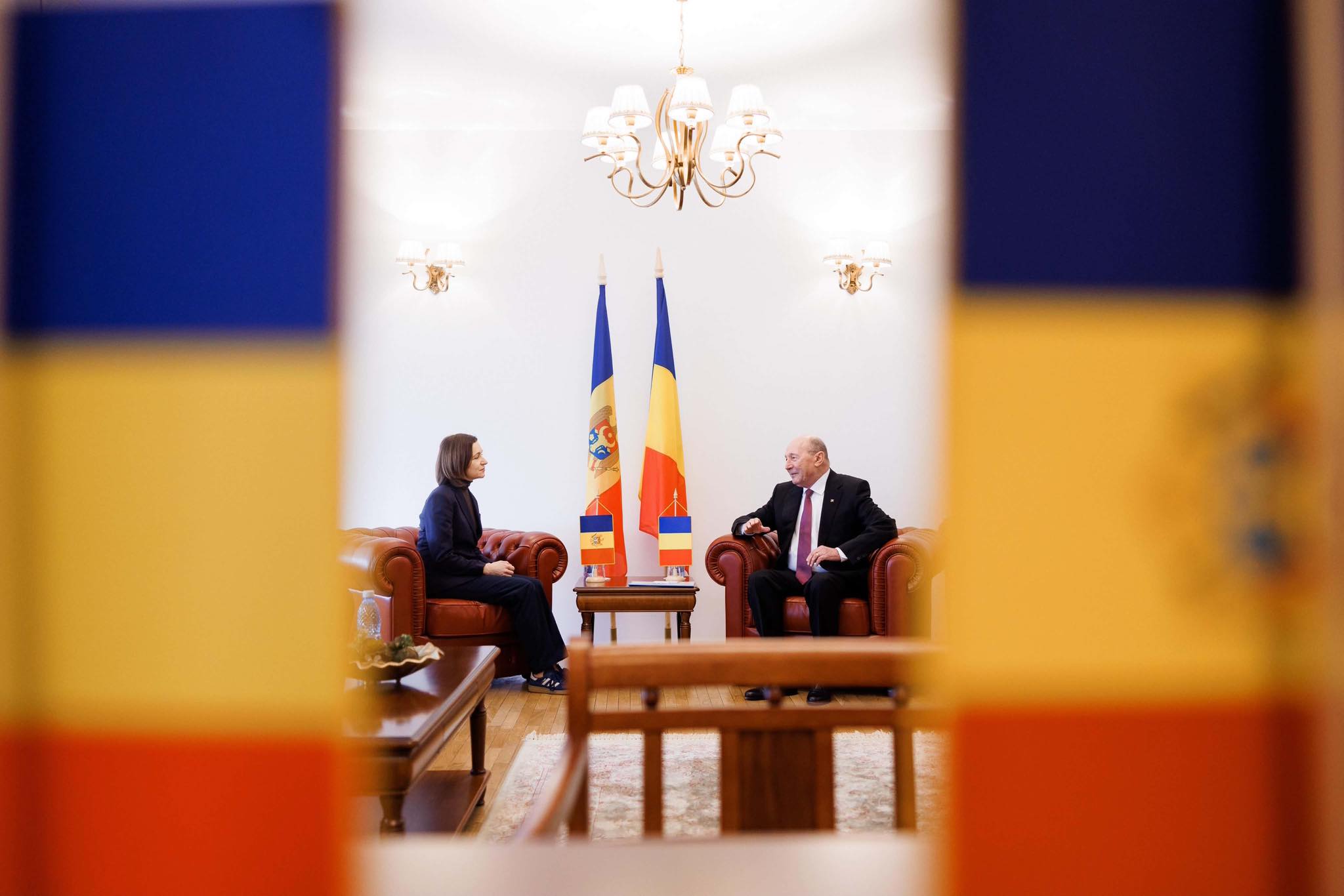 Maia Sandu și Traian Băsescu st&acirc;nd de vorbă, &icirc;nconjurați fiind de steagurile Rom&acirc;niei și Republicii Moldova