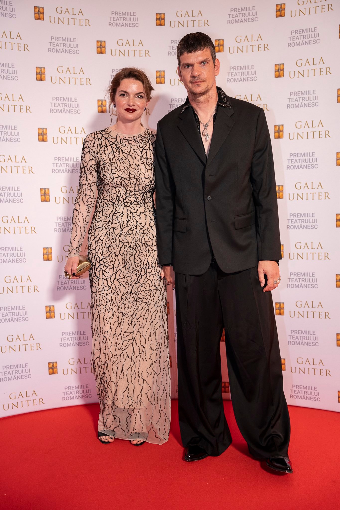 Tudor Chirilă și Iulia M&icirc;zgan la Gala Premiilor UNITER 2026, pe covorul roșu, &icirc;mbrăcați elegant, &icirc;n costum negru și rochie bej cu imprimeu