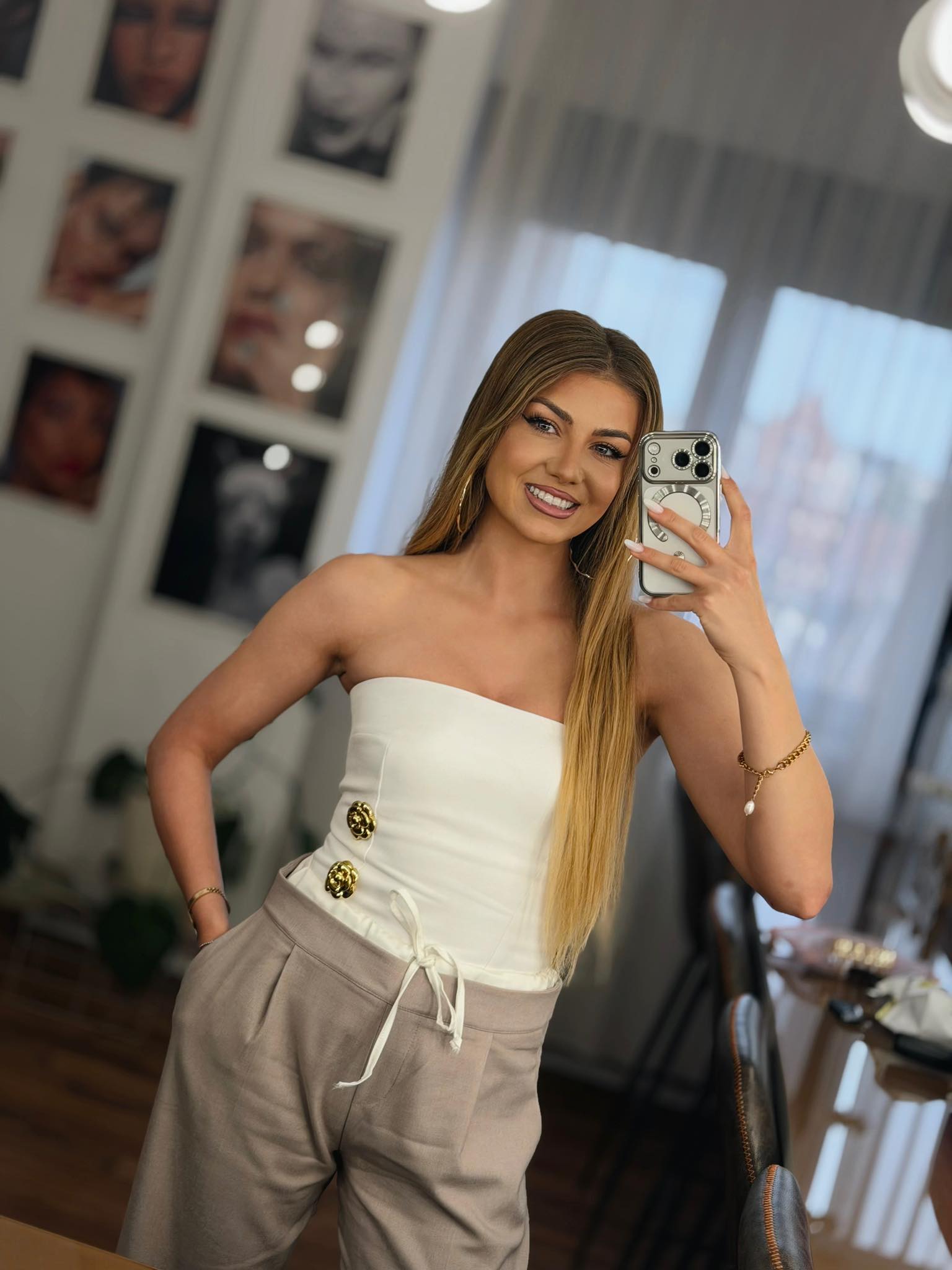 Codruța Filip admir&acirc;ndu-se &icirc;n oglindă și făc&acirc;ndu-și un selfie, după ce s-a machiat profesional, &icirc;n timp ce era &icirc;mbrăcată &icirc;n pantaloni gri și top alb