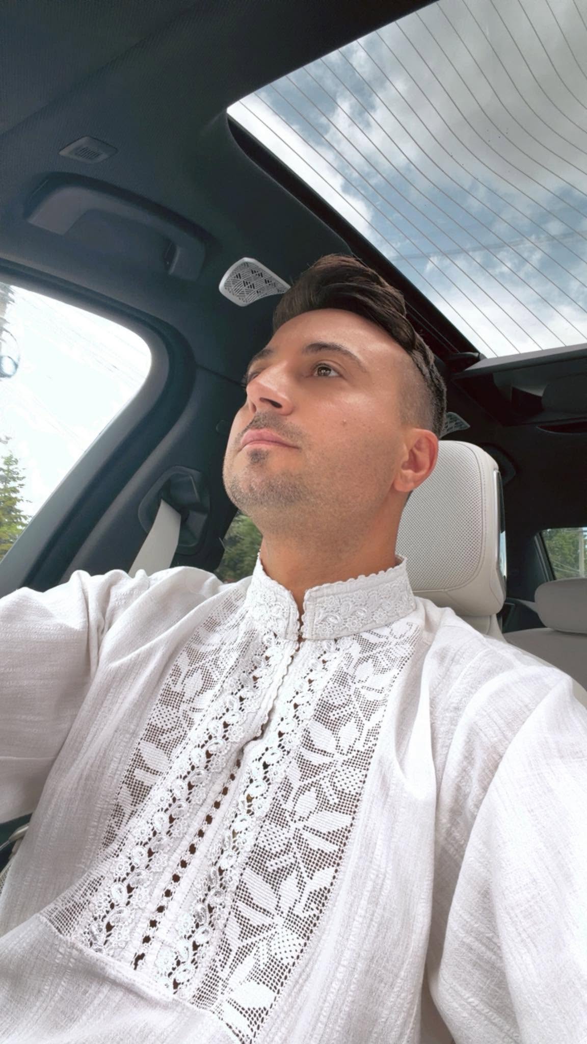 Valentin Sanfira în mașină, la volan, uitându-se la drum, în timp ce era îmbrăcat într-o ie albă