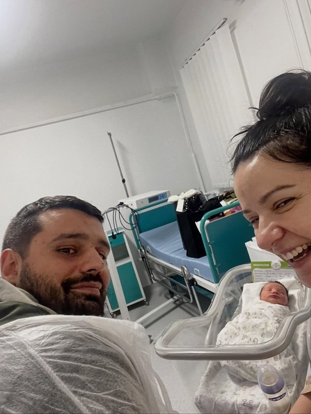 Anca&nbsp;Dinicu&nbsp;și Georgian Păun &icirc;n spital, z&acirc;mbitori, alături de fiul lor nou-născut, cu un biberon &icirc;ntre ei.