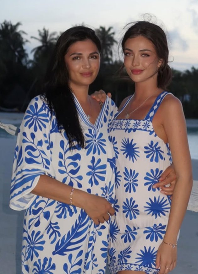 Andreea Bostănică alături de mama ei, la mare, &icirc;n timp ce eram am&acirc;ndouă &icirc;mbrăcate &icirc;n rochii albe cu imprimeu floral albastru
