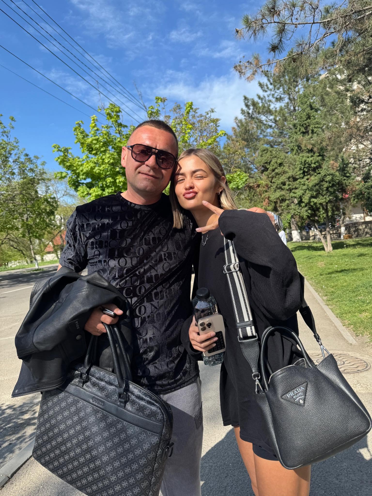 Iuliana Beregoi purt&acirc;nd o geantă pe umăr, alături de tatăl ei, care are o altă geantă &icirc;n m&acirc;nă și ochelari de soare la ochi