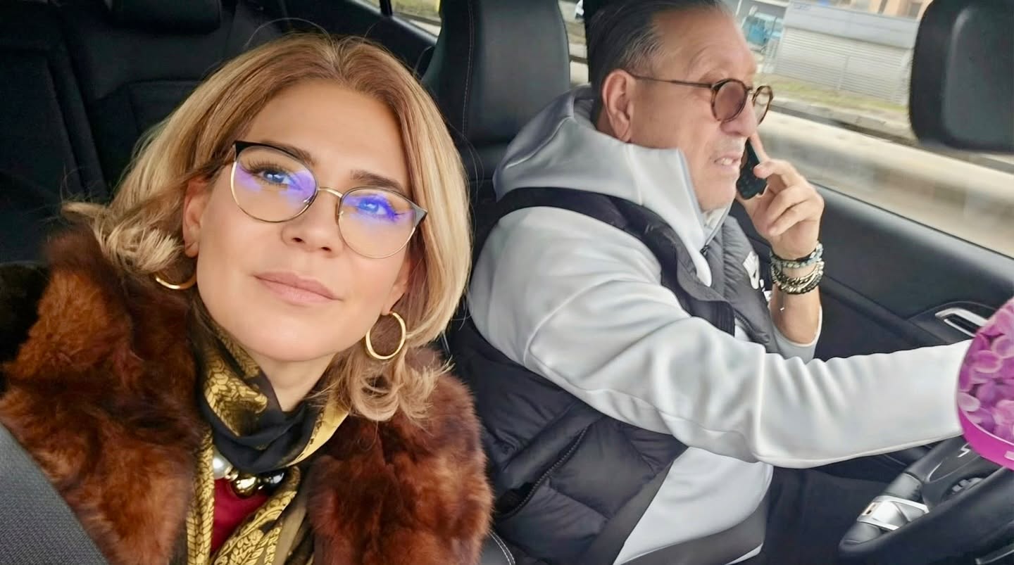 Serghei Mizil vorbind la telefon la volan, &icirc;n timp ce soția sa, Cora Mizil, făcea un selfie pe scaunul din dreapta, iar el se vede &icirc;n fundal