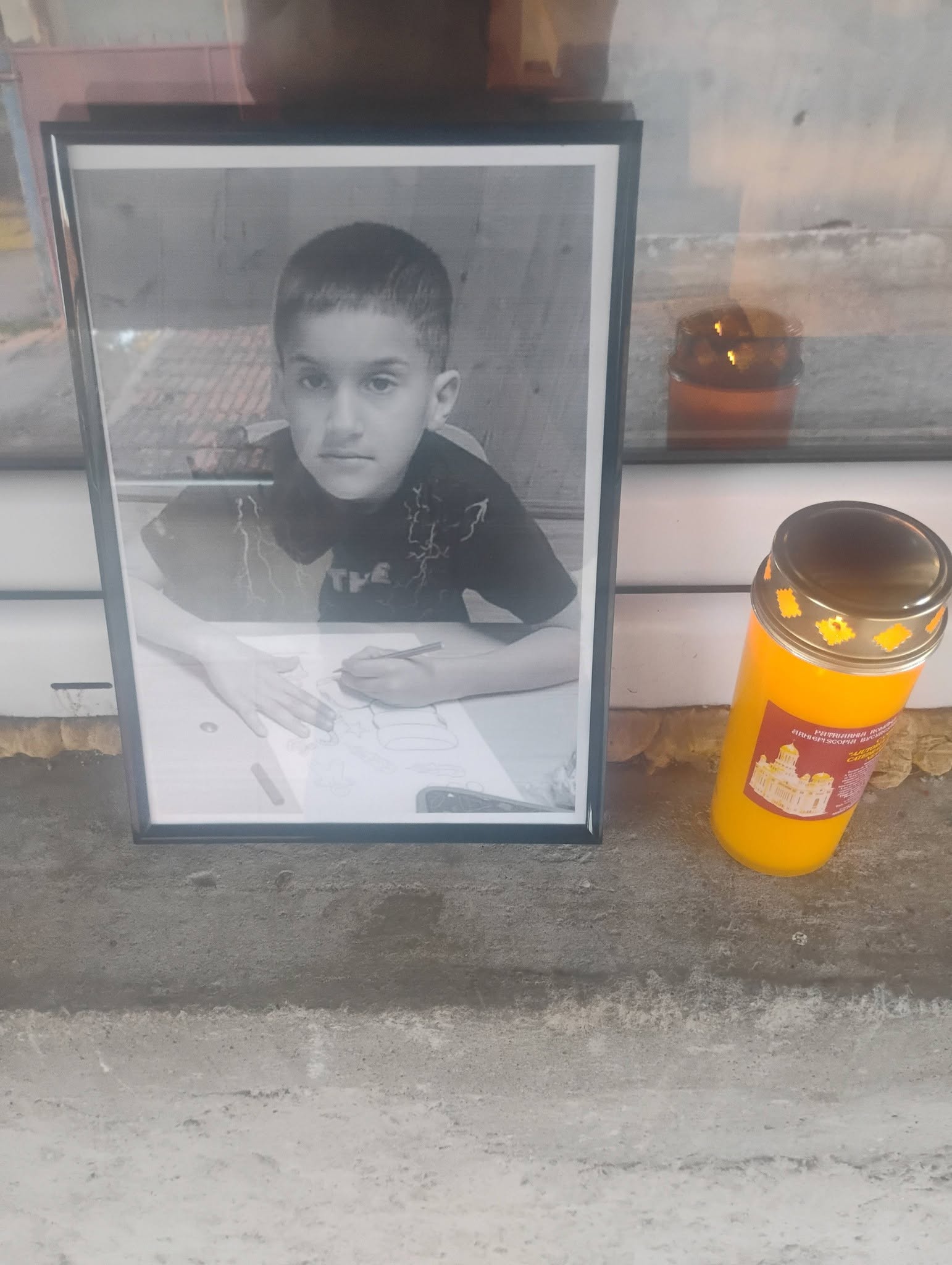 Fotografia lui Darius Petrescu așezată pe un pervaz, cu o lumânare aprinsă lângă ea