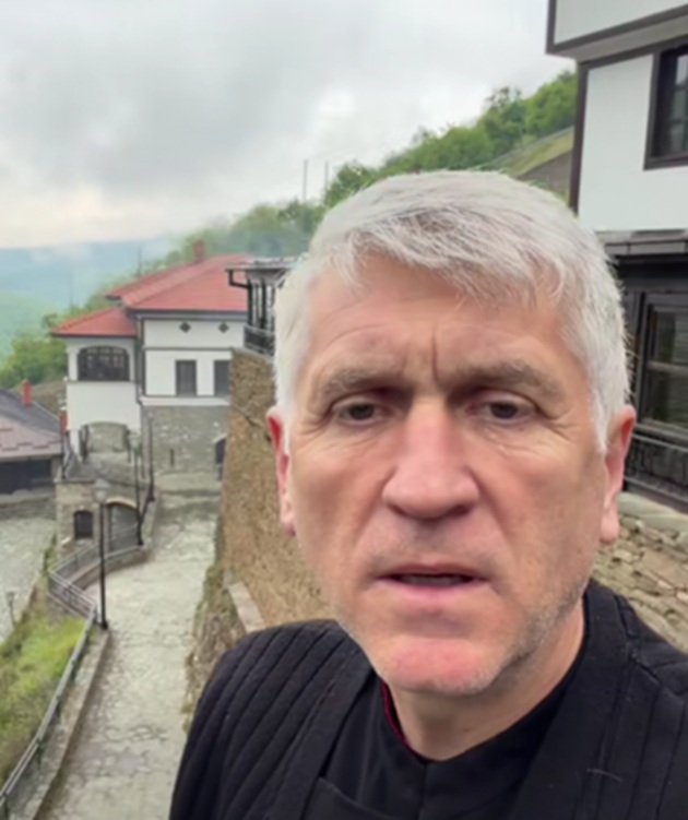Cristian Pomohaci st&acirc;nd serios la cameră, &icirc;mbrăcat &icirc;n negru, &icirc;n timp ce se afla &icirc;n vizită la o mănăstire