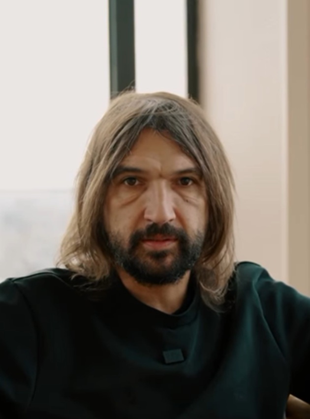 Dan Alexa în timpul unui interviu, cu părul desfăcut, îmbrăcat într-un tricou negru, stând serios în fața camerei