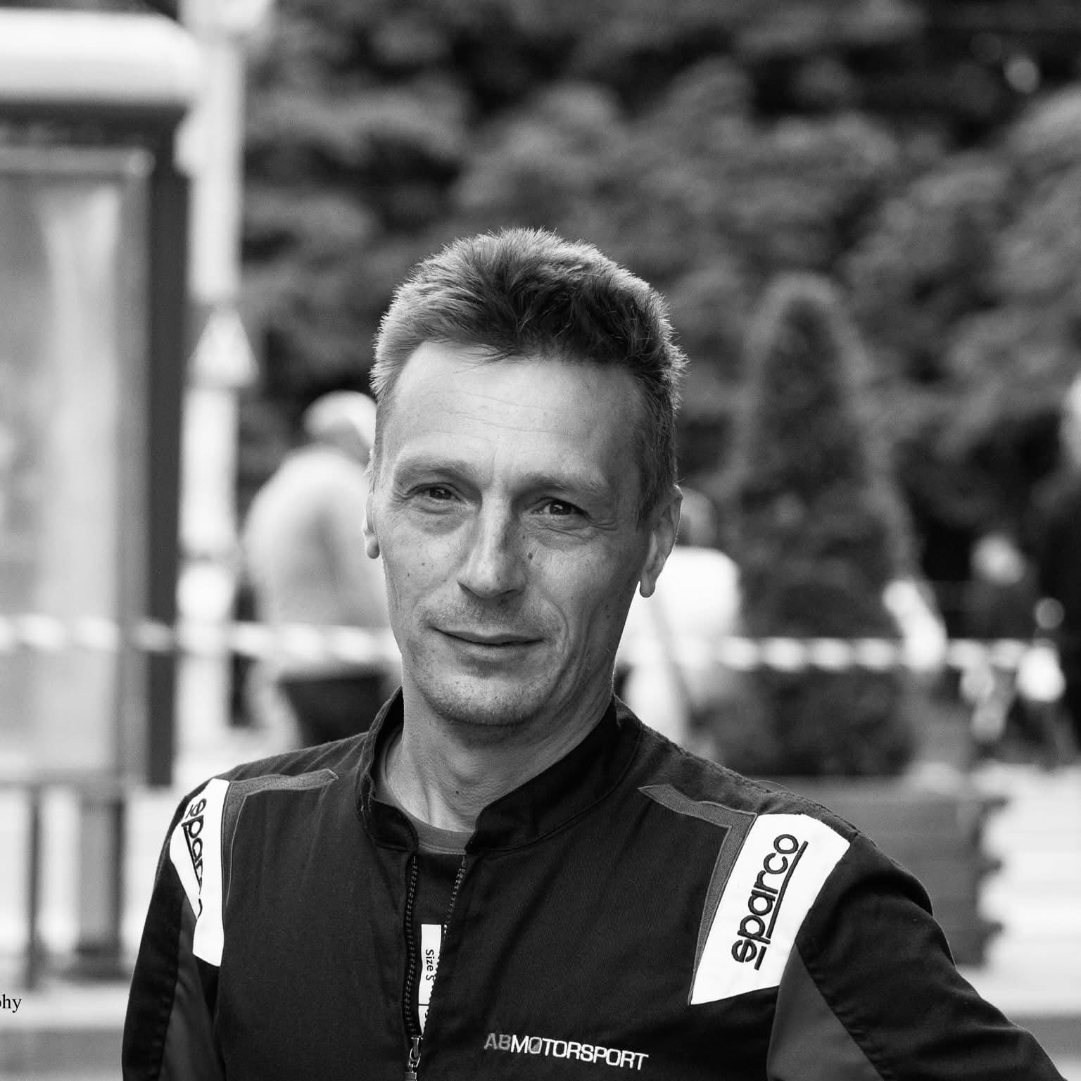 Imagine alb-negru cu pilotul Alex Berea &icirc;mbrăcat &icirc;n echipamentul sportiv, &icirc;n cadrul uneia dintre cursele la care a participat