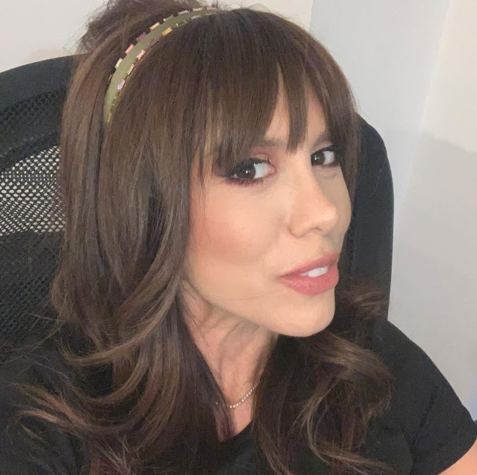 Denise Rifai făc&acirc;ndu-și un selfie &icirc;n timp ce stătea pe un scaun de birou, &icirc;mbrăcată &icirc;n negru, cu o cordeluță verde pe cap.