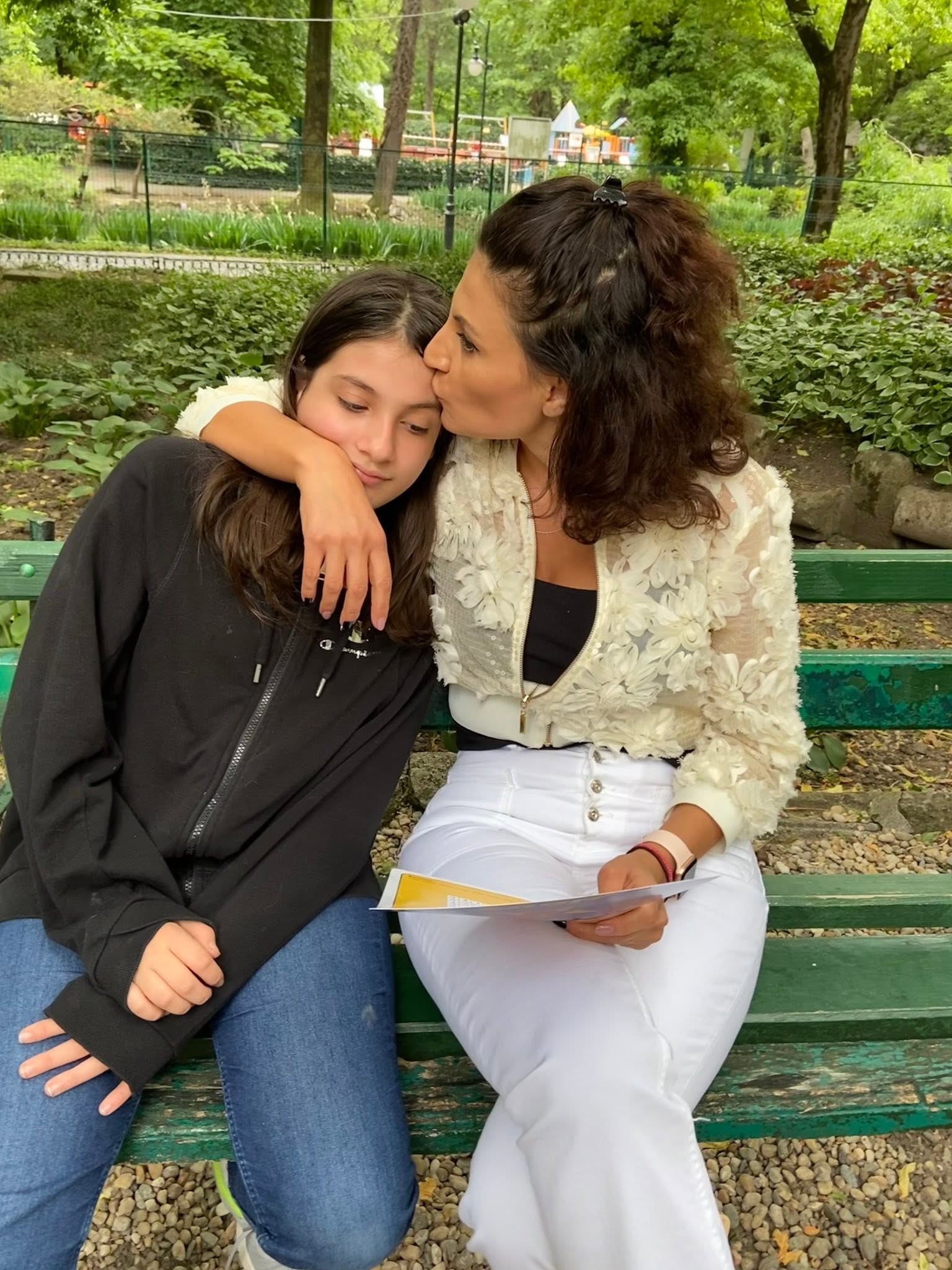 Ioana Ginghină &icirc;mbrățiș&acirc;nd-o pe fiica ei și sărut&acirc;nd-o pe t&acirc;mplă, &icirc;n timp ce stăteau m&acirc;ndouă pe o bancă, &icirc;n parc.