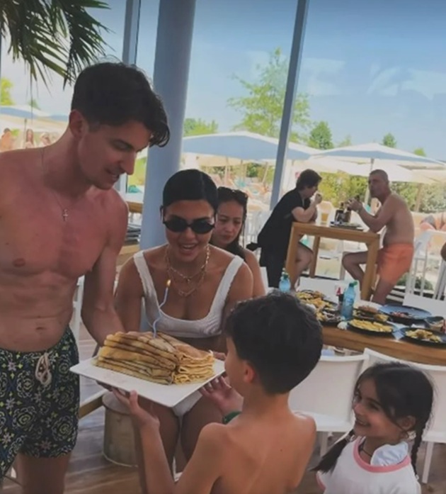 Andreea Popescu și Rareș Cojoc ținând împreună un tort de clătite la petrecerea fiului lor Ioachim, la piscină