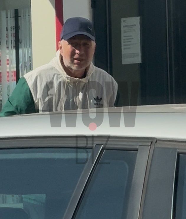 Dan Petrescu pe trotuar, în spatele unei mașini, în timp ce se plimba pe jos, îmbrăcat în hanorac și cu șapcă pe cap