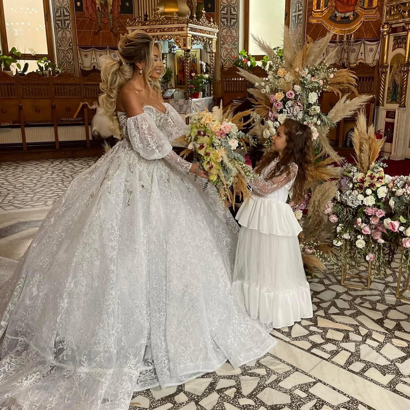 Roxana Vașniuc mireasă, la biserică, alături de fetița ei, &icirc;mbrăcată și ea &icirc;n rochie albă, &icirc;nconjurate de multe flori