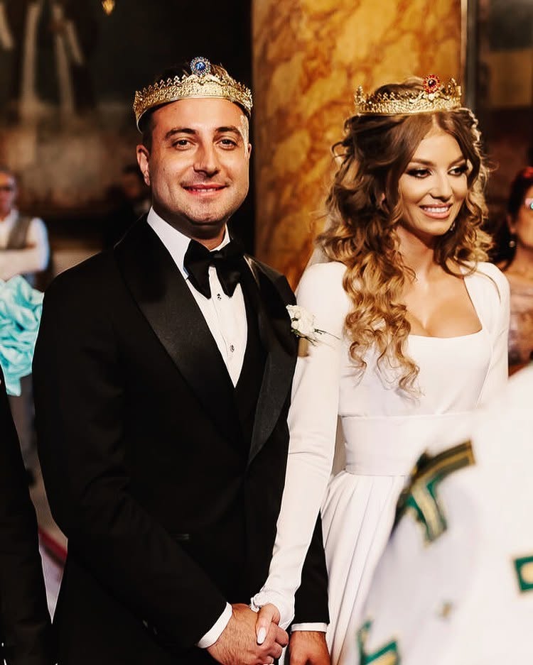 Valentin Sanfira și Codruța Filip &icirc;n ziua nunții, țin&acirc;ndu-se de m&acirc;nă &icirc;n biserică, &icirc;mbrăcați &icirc;n mire și mireasă, cu cununiile pe cap